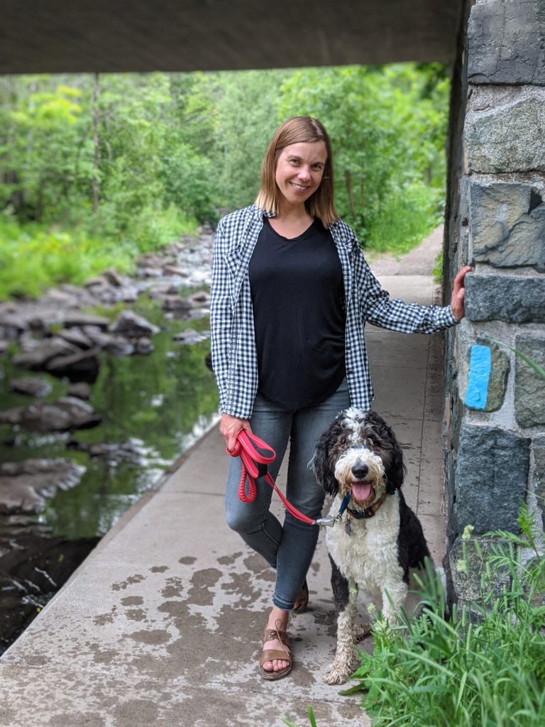 Lisa Luokkala, Executive Director, standing near a stream with dog